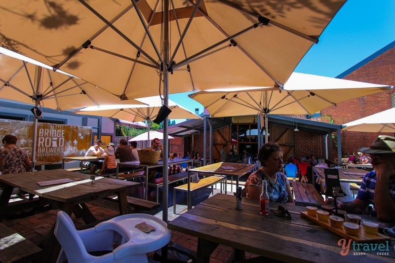 people sitting on picnic tables under umbrellas