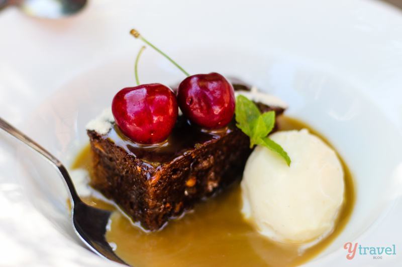 sticky date topped with cherries and cream on a plate