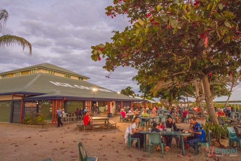 people sitting on tables and chairs on sand outside Pub at Karumba 