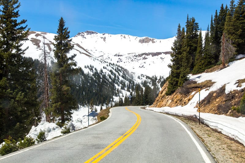 road winding through snow covered mountains in colorado