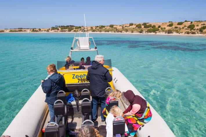 people on a boat with turquoise water and nearby island