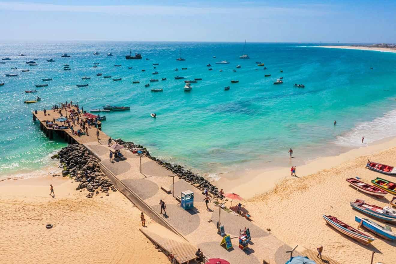 An aerial view of a beach with boats moored in the water.