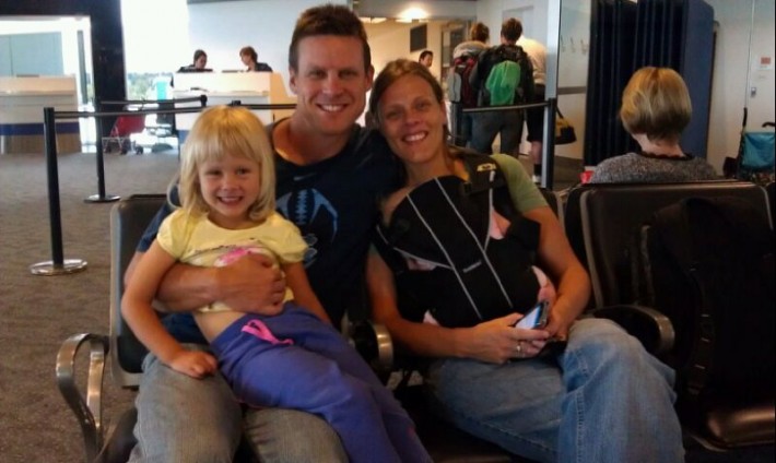 family in airport with baby smiling at camera