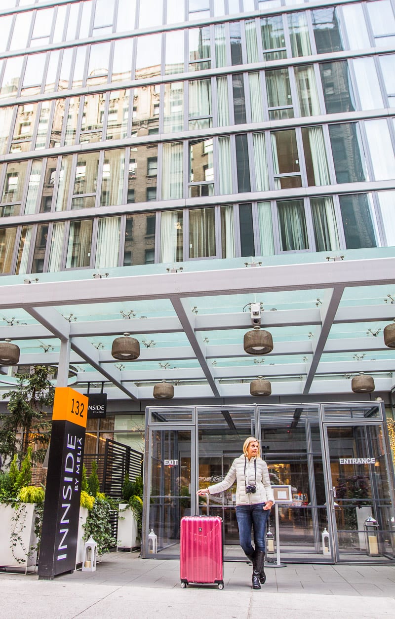 woman standing outside hotel with suitcase