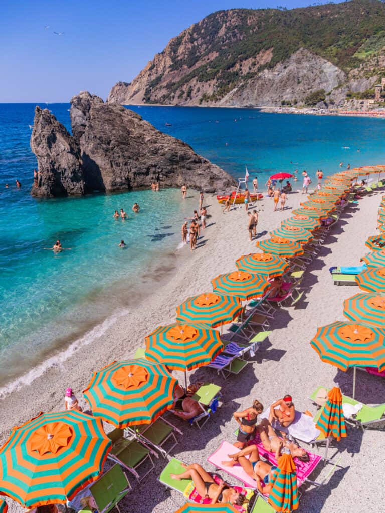 loungers and umbrellas on the beach with rock just offshore