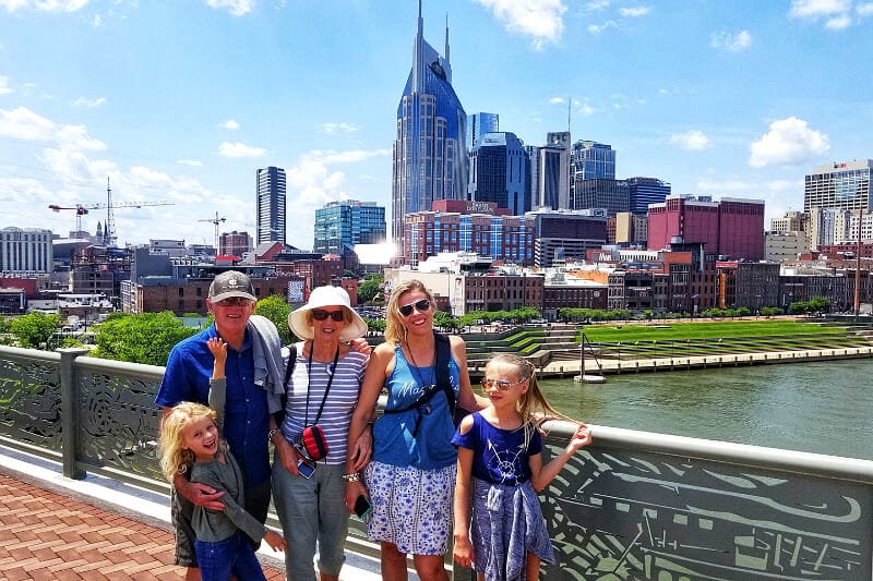 people standing on a bridge with a city skyline