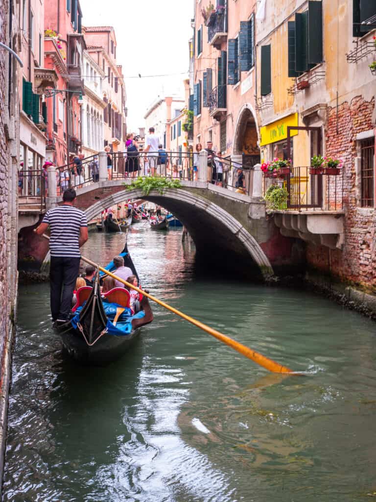 man rowing gondola down venice canal