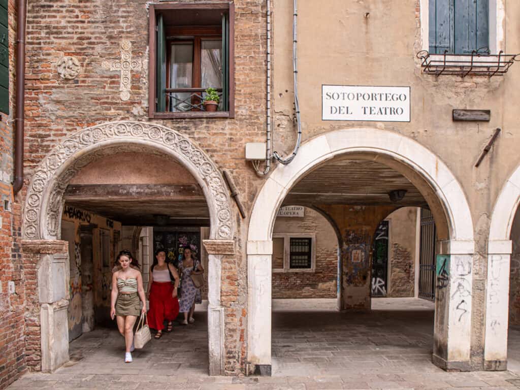 girl walking under archway into square