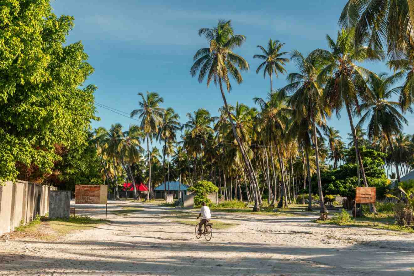 A person riding a bike on a sandy street in Jambiani town in Zanzibar