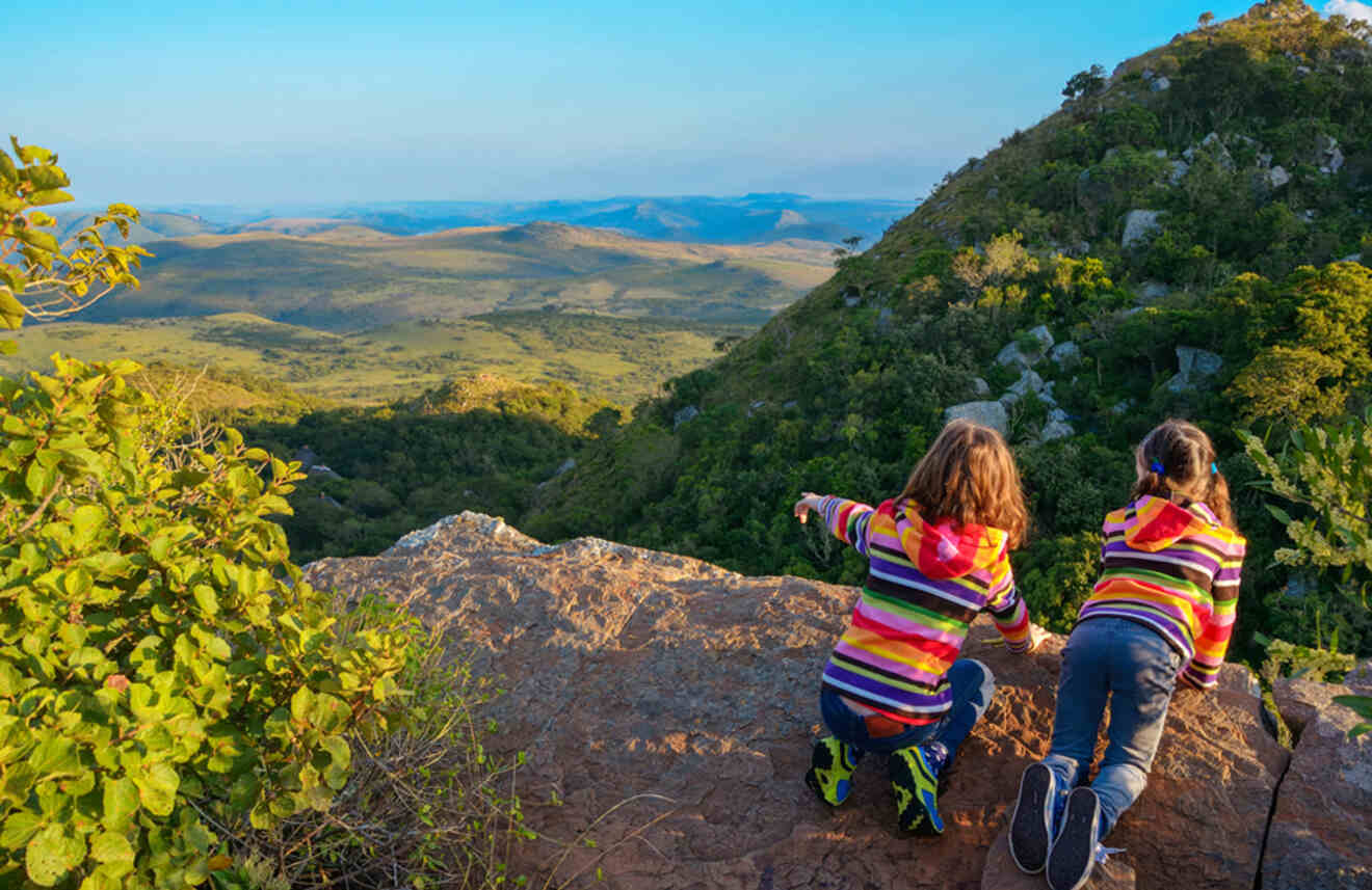 two girls standing on a cliff pointing towards the landscape