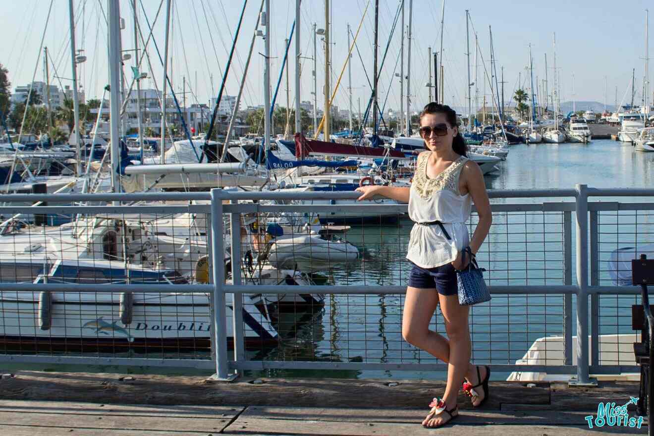 A woman standing on a dock with boats in the background.