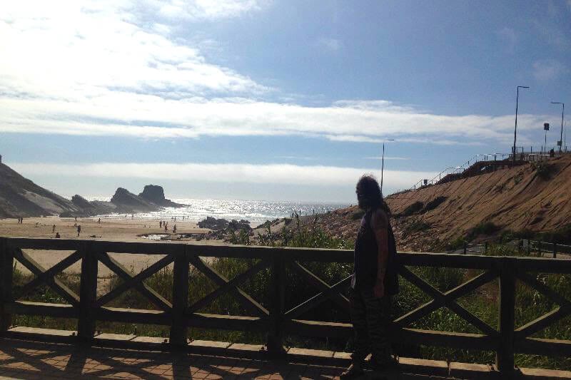 person walking beside Praia da Zambujeira do Mar 