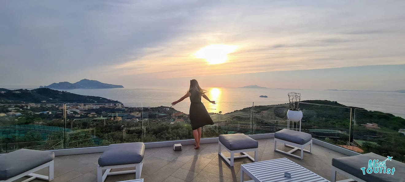 A woman is standing on a balcony overlooking the ocean at sunset in a hotel in Sorrento, Amalfi Coast, Italy