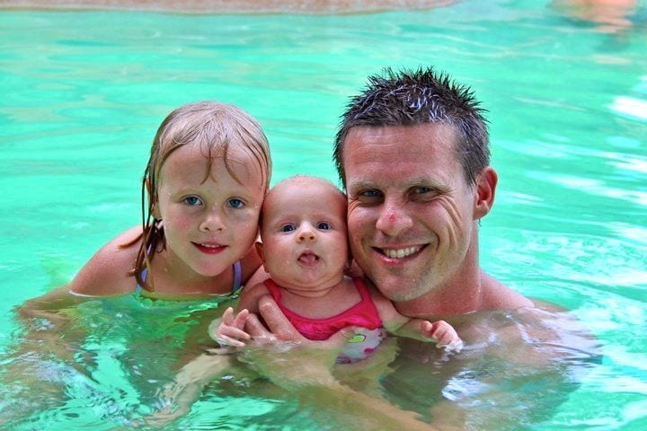 man. child and baby swimming in thermal pool