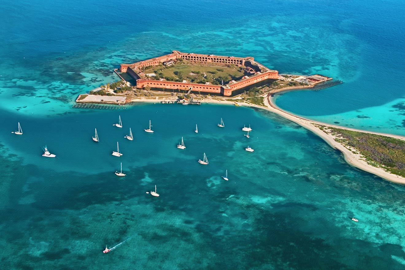 An aerial view of an island with sailboats in the water.