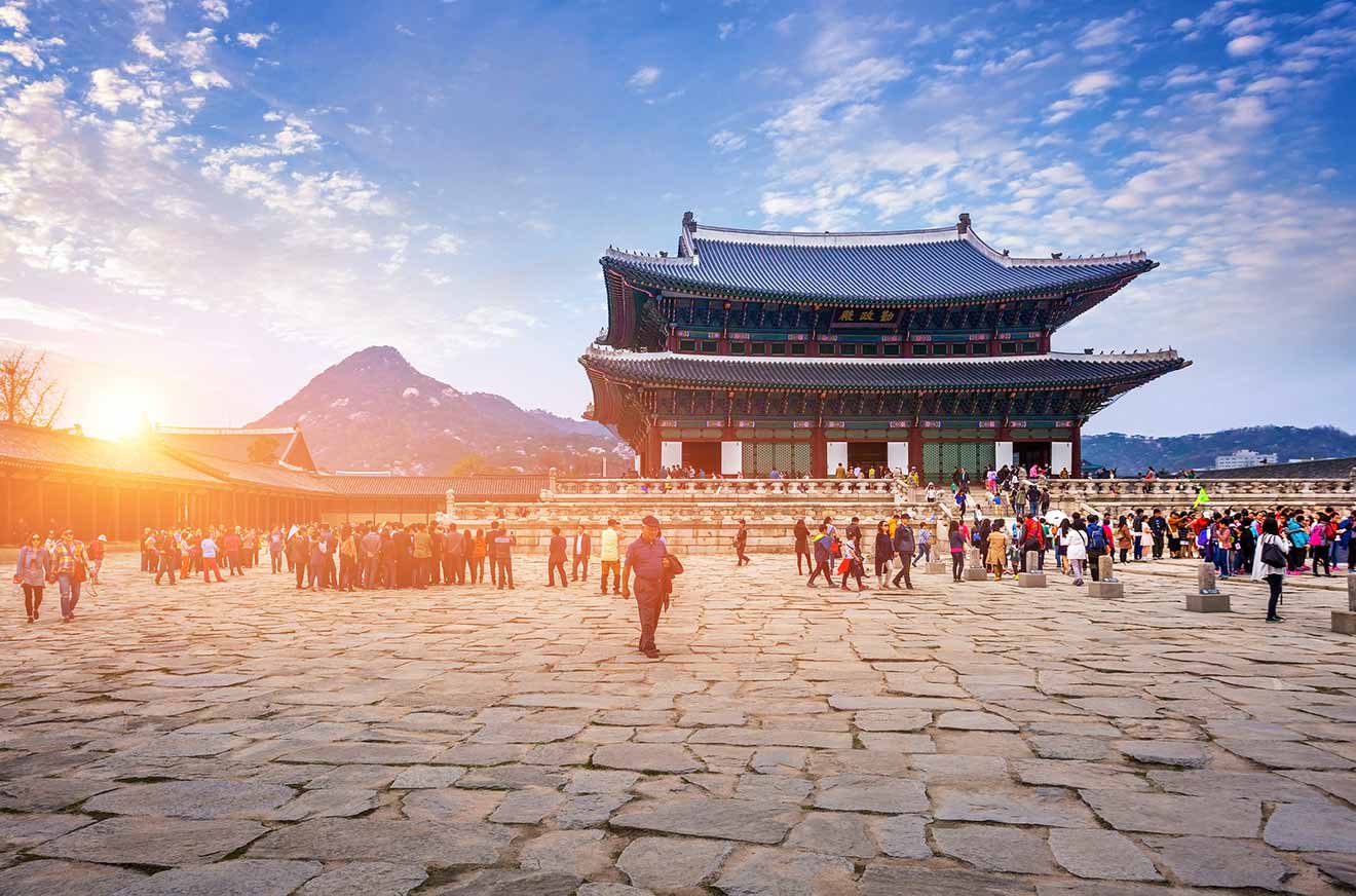 A group of people standing in front of a pagoda in seoul, south korea at sunset