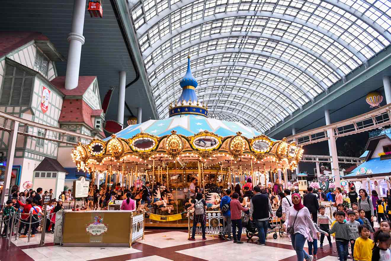 A carousel in a shopping mall in seoul with people walking around.