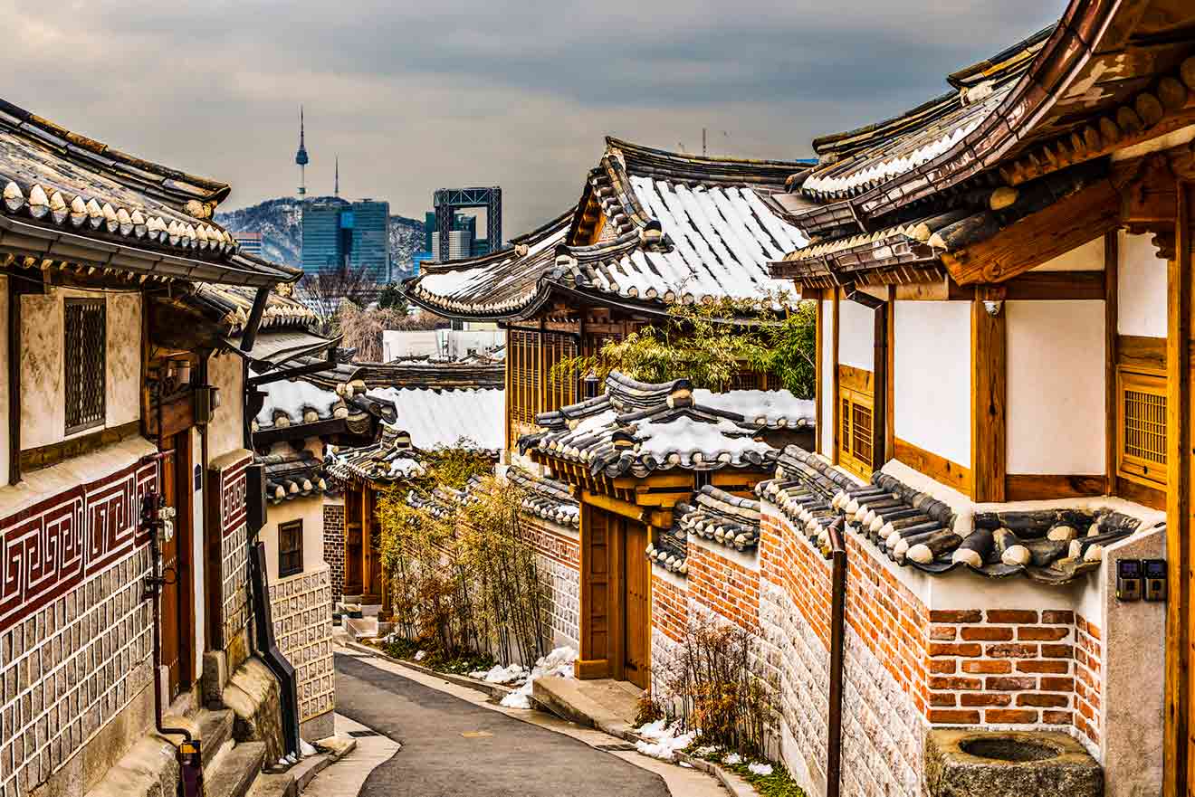 A street lined with korean buildings and seoul city in the background.