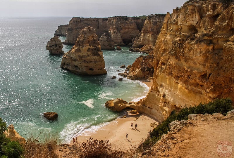 small cove beach at bottom of giant cliffs in the algarve