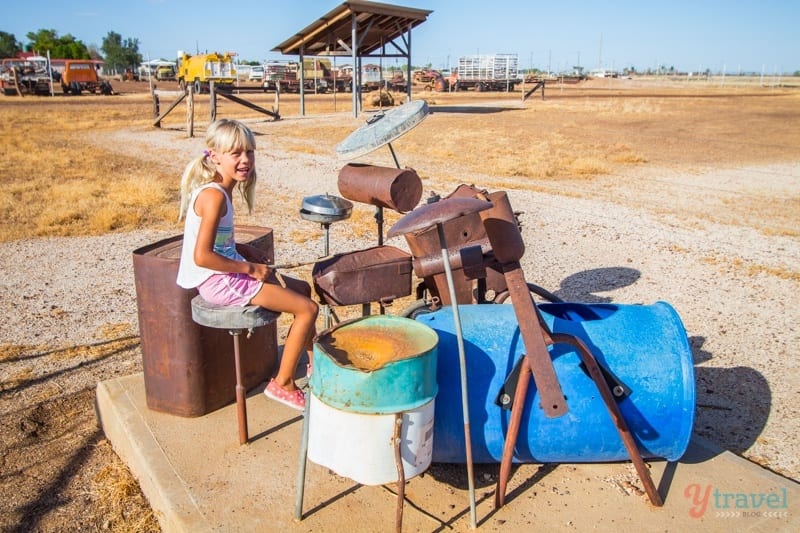 girl sitting on a stool in front of a fake drum set