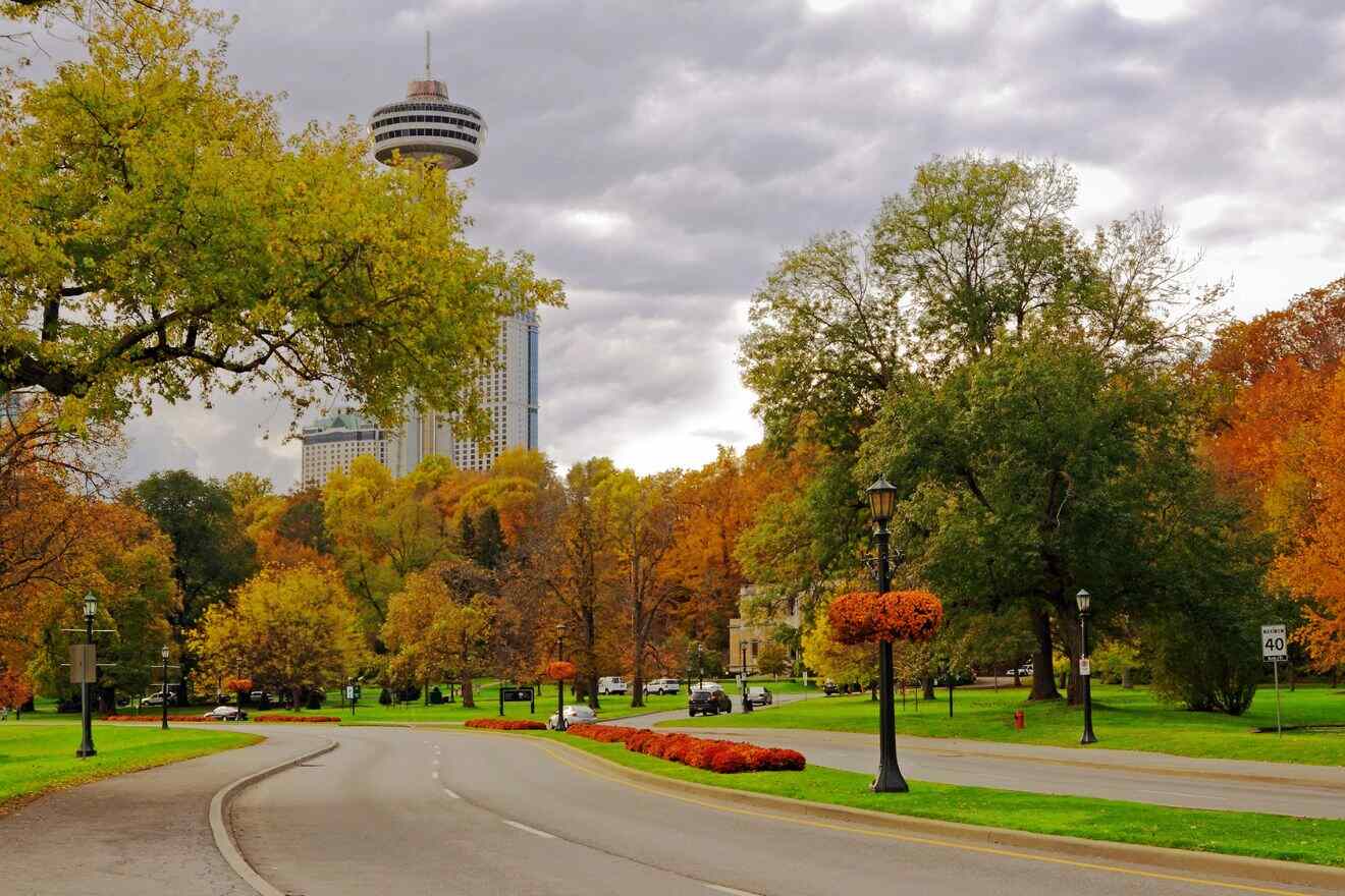 Scenic drive along Niagara Parkway, flanked by trees showing autumn colors and the Skylon Tower in the backdrop.