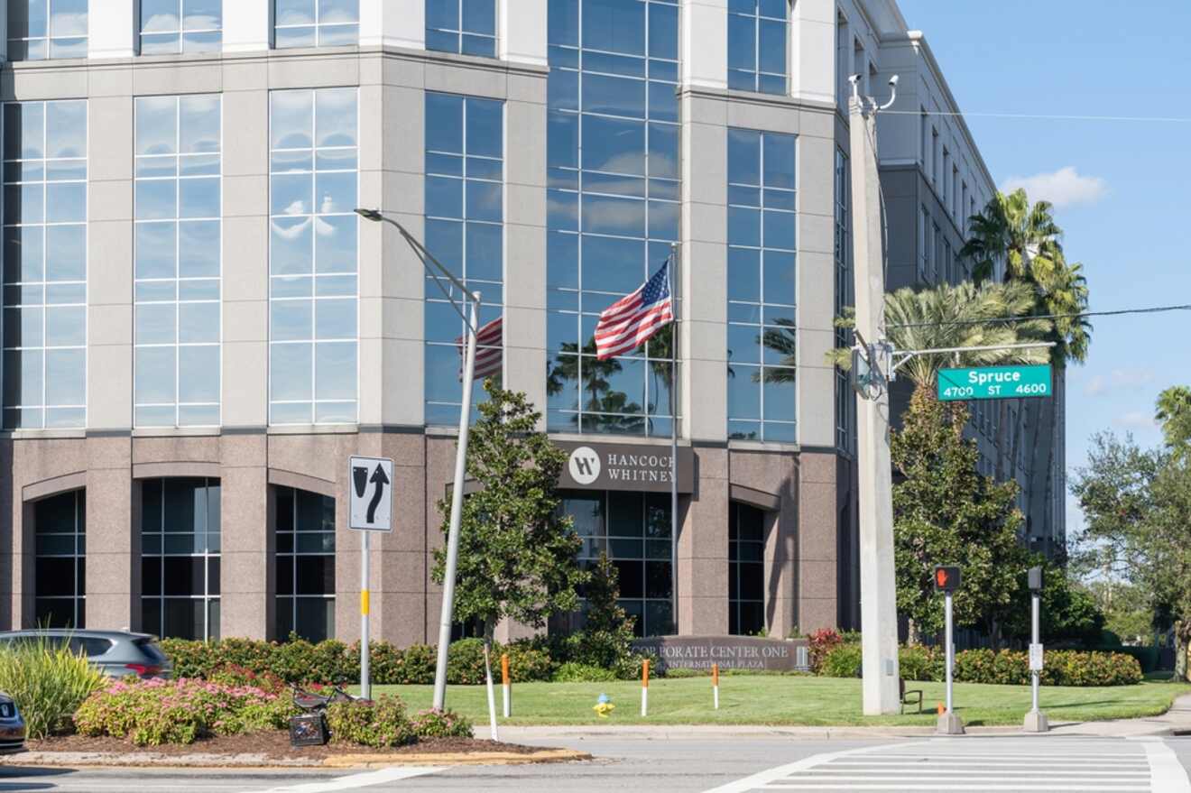 Modern office building with reflective windows and the American flag, under a clear blue sky