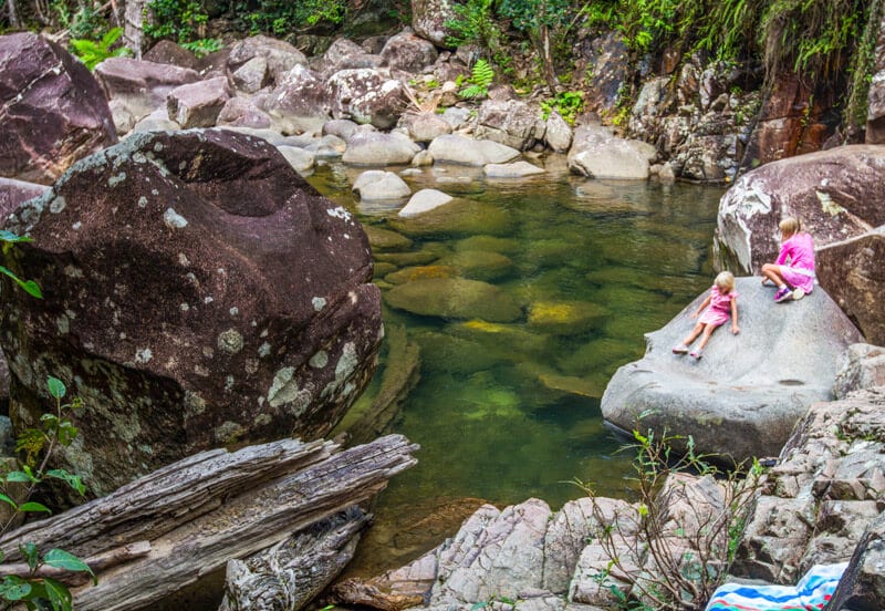 girls sitting on rock looking into arulen swimming hole