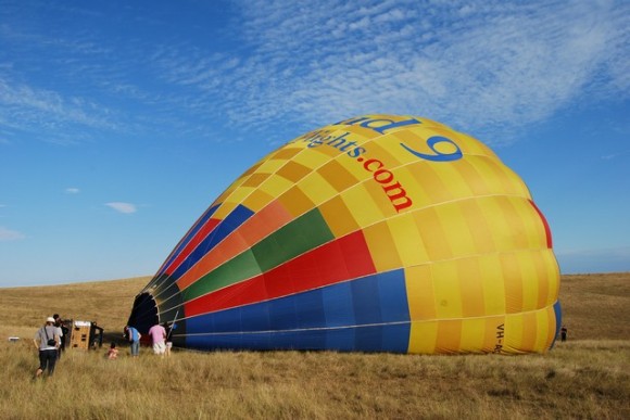 hot air balloon on its side getting blown up on the grass