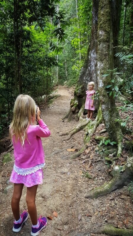 girl taking photo of sister next to tree