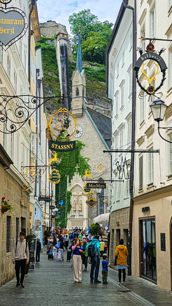 street in old town salzburg lined with stores and church at theend