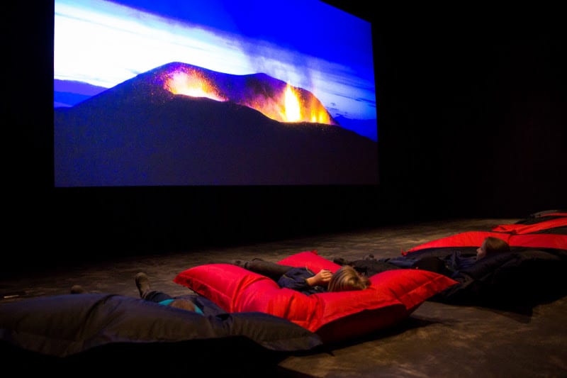 people lying on floor watching movie at the Lava centre, Iceland