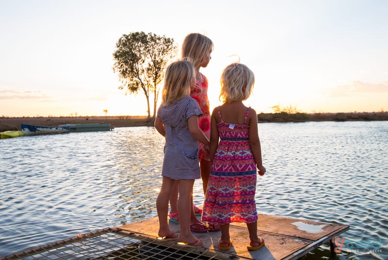 young girls holding hands looking at billabong