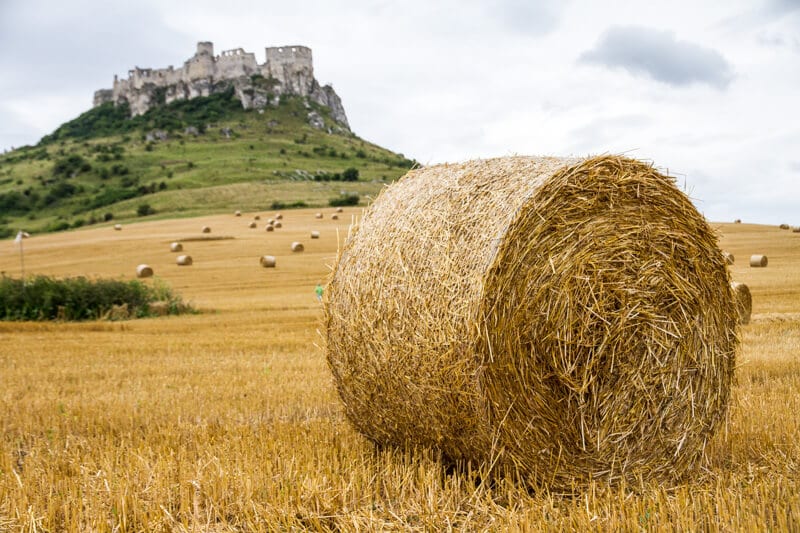 giant hay stack with Spis Castle Slovakia on the hill behind