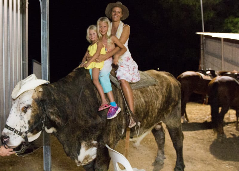 woman and two kids sitting on cow