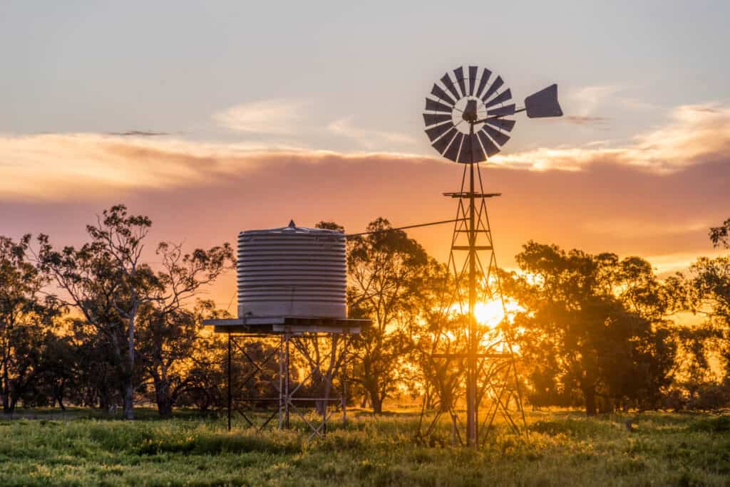 Sun sets over a water tank and windmill in Gulargambone. | 