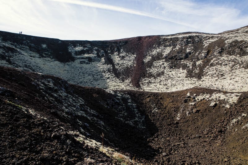 people walking on rim of volcano