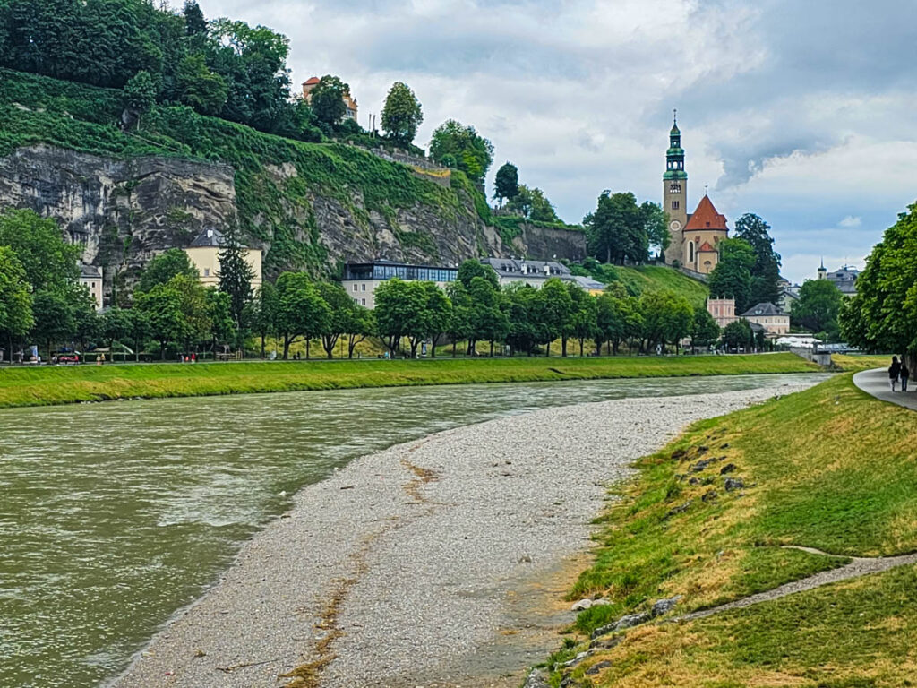 river running through Salzburg with buildings on hilltops