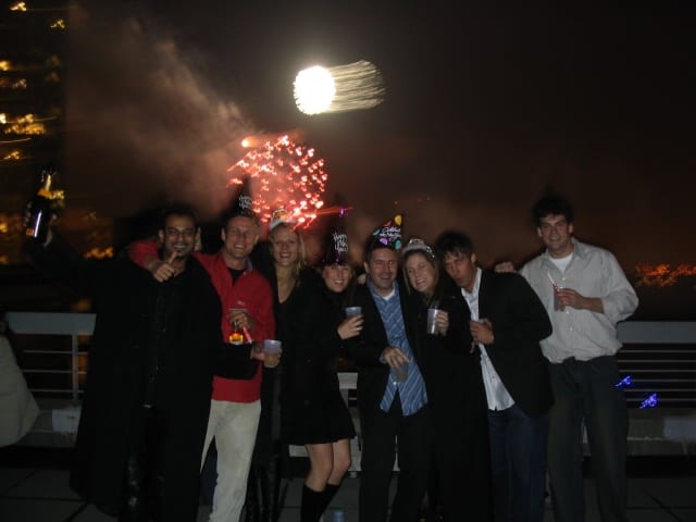 friends on rooftop on new york with fireworks behind them onNew Years Eve, New York City