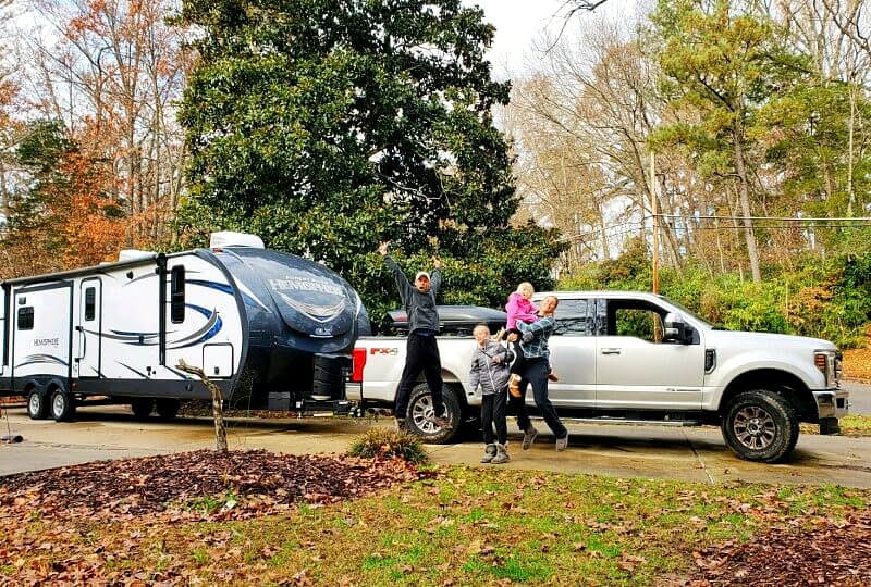 family posing in front of Forest River travel trailer and Ford f250