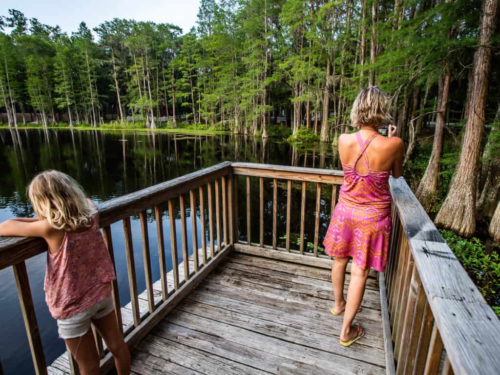 Mom and daughter on a deck overlooking a pond.