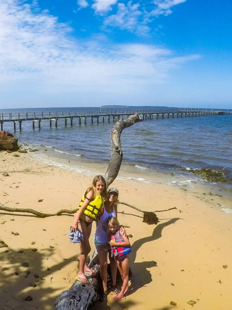 Mom and two daughters on an island having a photo on a tree log.