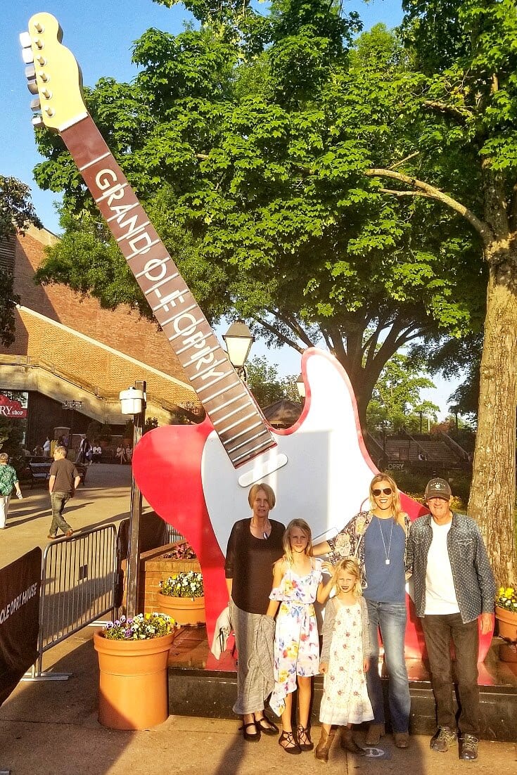 family posing in front of guitar