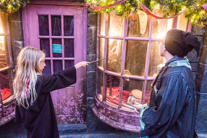 girl pointing a toy wand at a window