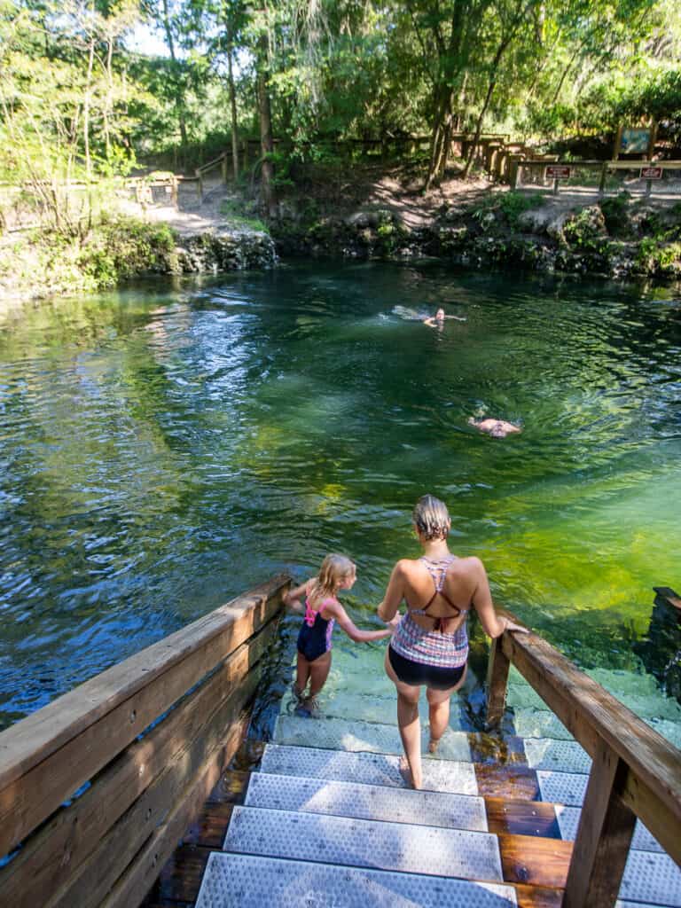 Mom and daughter entering s spring swimming hole.