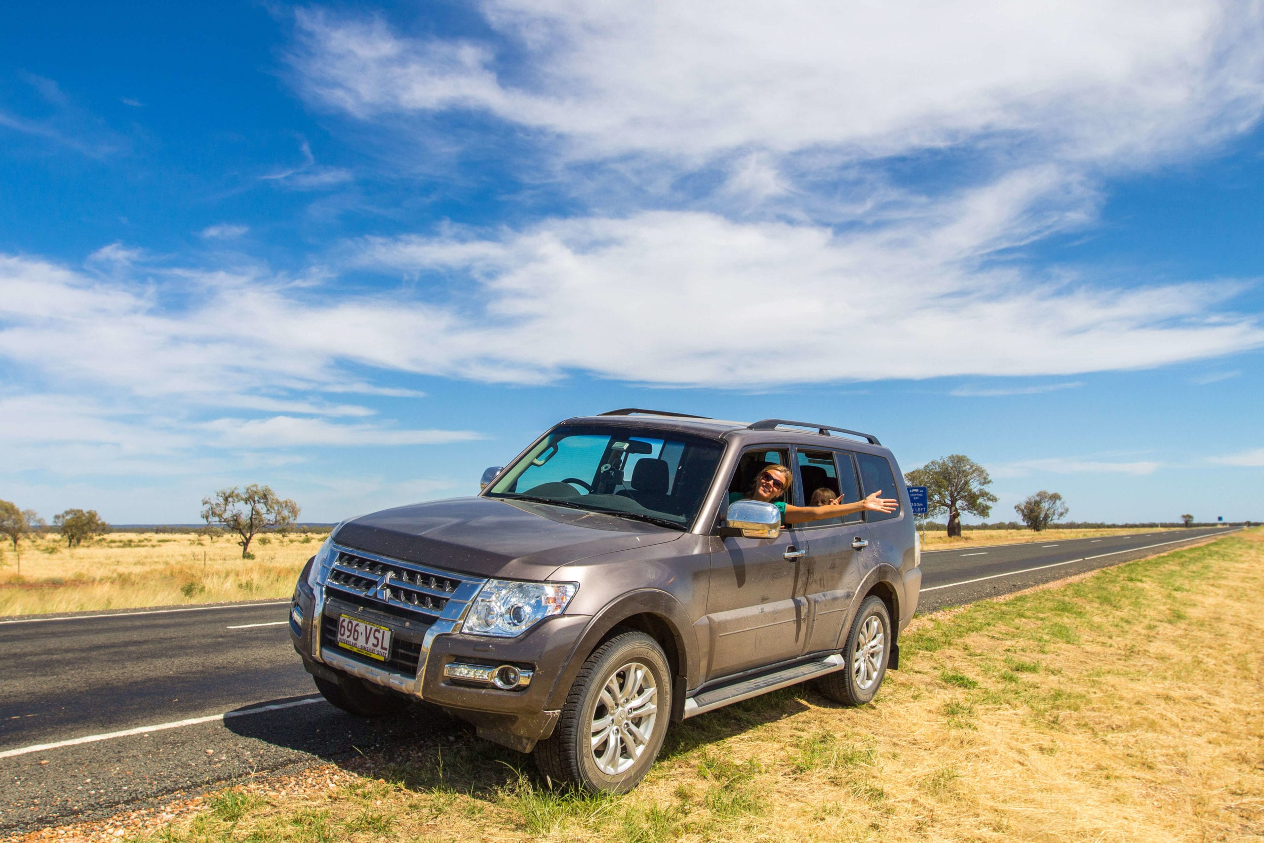 lady haning out of car in the outback