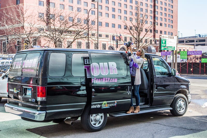 woman standing beside prince tour bus