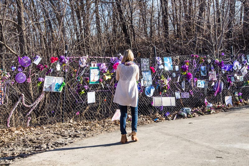 woman standing in front of a fence with signs on it