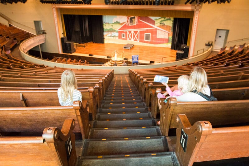 people sitting on pews looking at stage On tour at the Ryman Auditorium