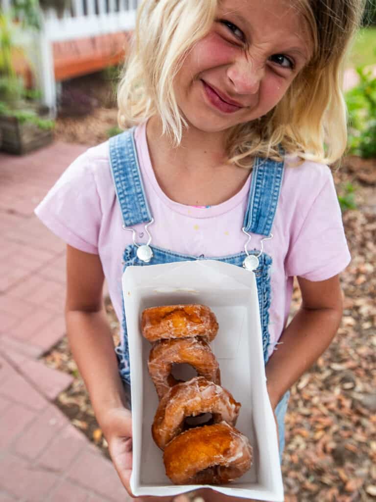 Girl holding a box of donuts.