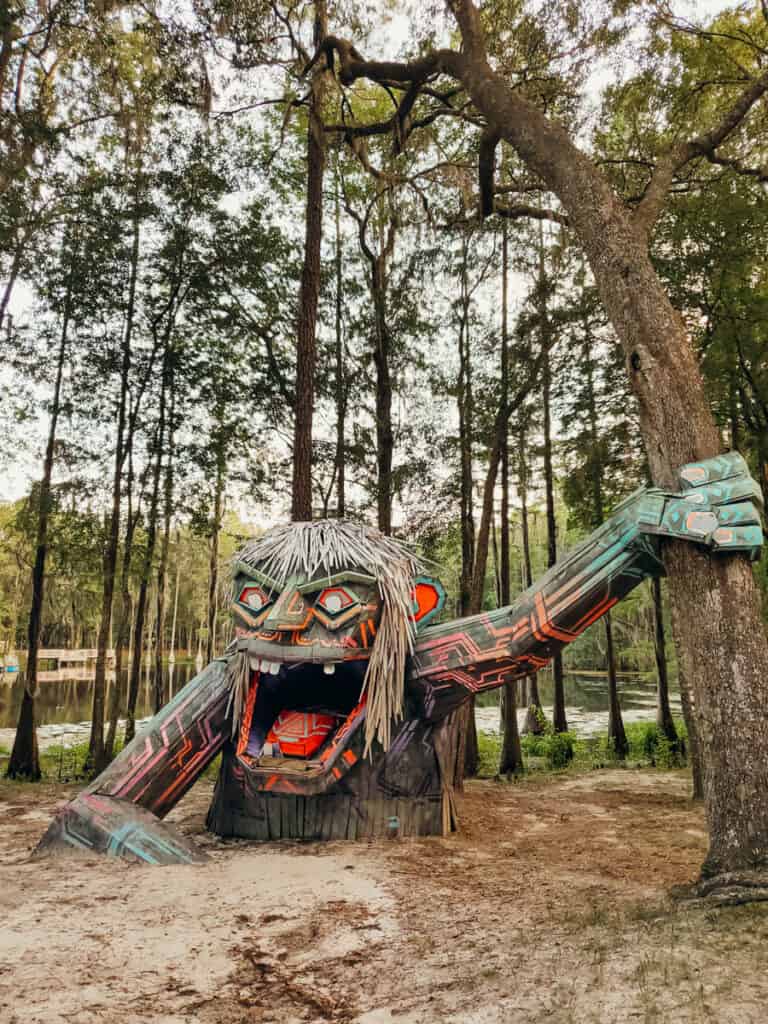 giant troll sculpture holding onto tree